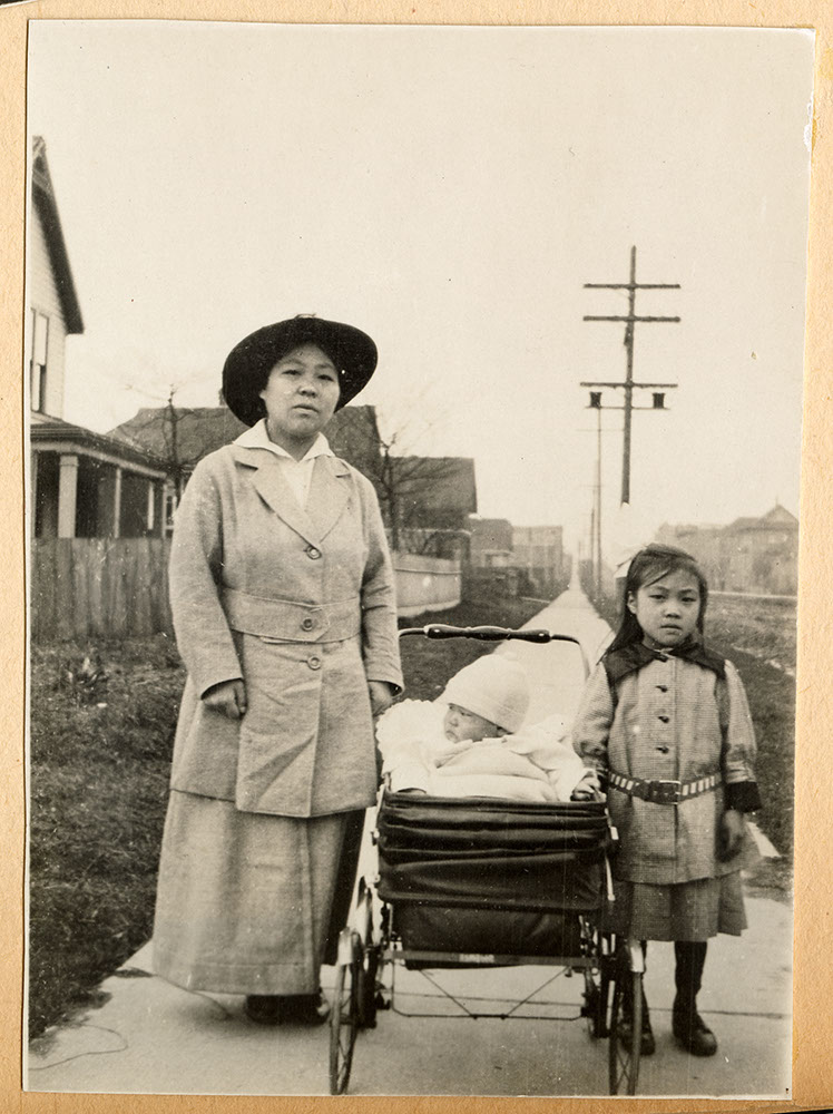 Unidentified woman with two children on the sidewalk
